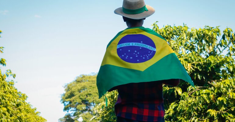 Farmer at coffee plantation holding Brazilian flag