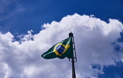 Low angle shot of the flag of Brazil under the beautiful clouds in the blue sky