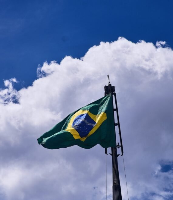 Low angle shot of the flag of Brazil under the beautiful clouds in the blue sky