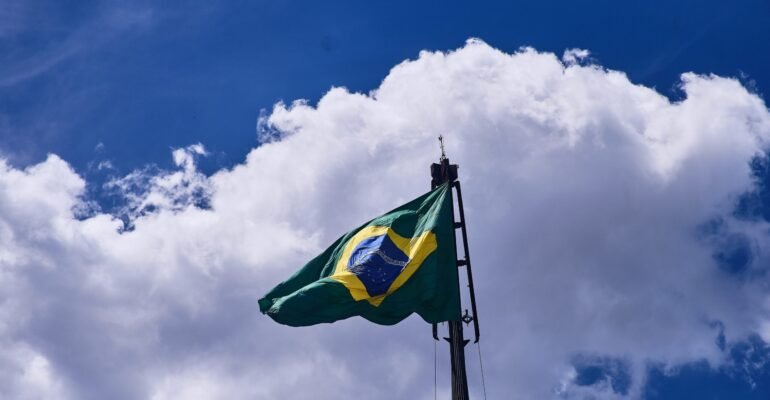 Low angle shot of the flag of Brazil under the beautiful clouds in the blue sky