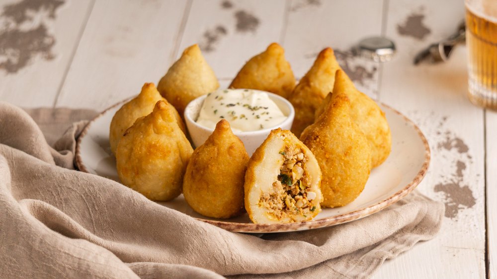 Brazilian coxinhas with one cut open to show the chicken filling