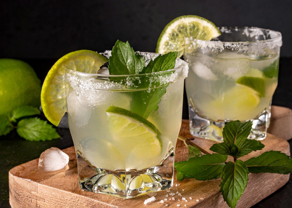 Two Brazilian lime caipirinhas with ice and mint garnish