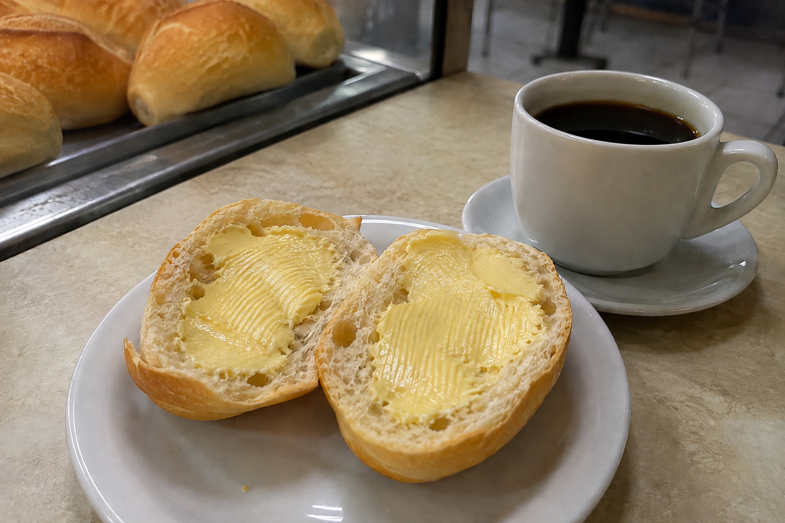 Brazilian pão com manteiga served with coffee at a traditional bakery